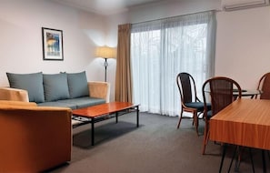 Habitación de hotel con sofá, mesa de comedor, lámpara y silla.