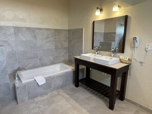 Ein Badezimmer mit einer Badewanne, zwei Waschbecken, einem Spiegel und einem Fön.