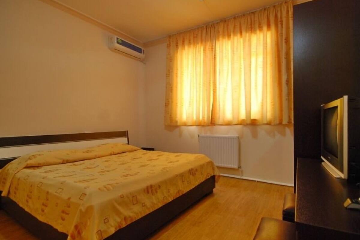 Une chambre d’hôtel avec un lit, une télévision, un radiateur et des rideaux.