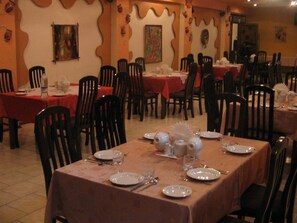 A dining area with multiple tables, each set with plates, cutlery, and glasses.