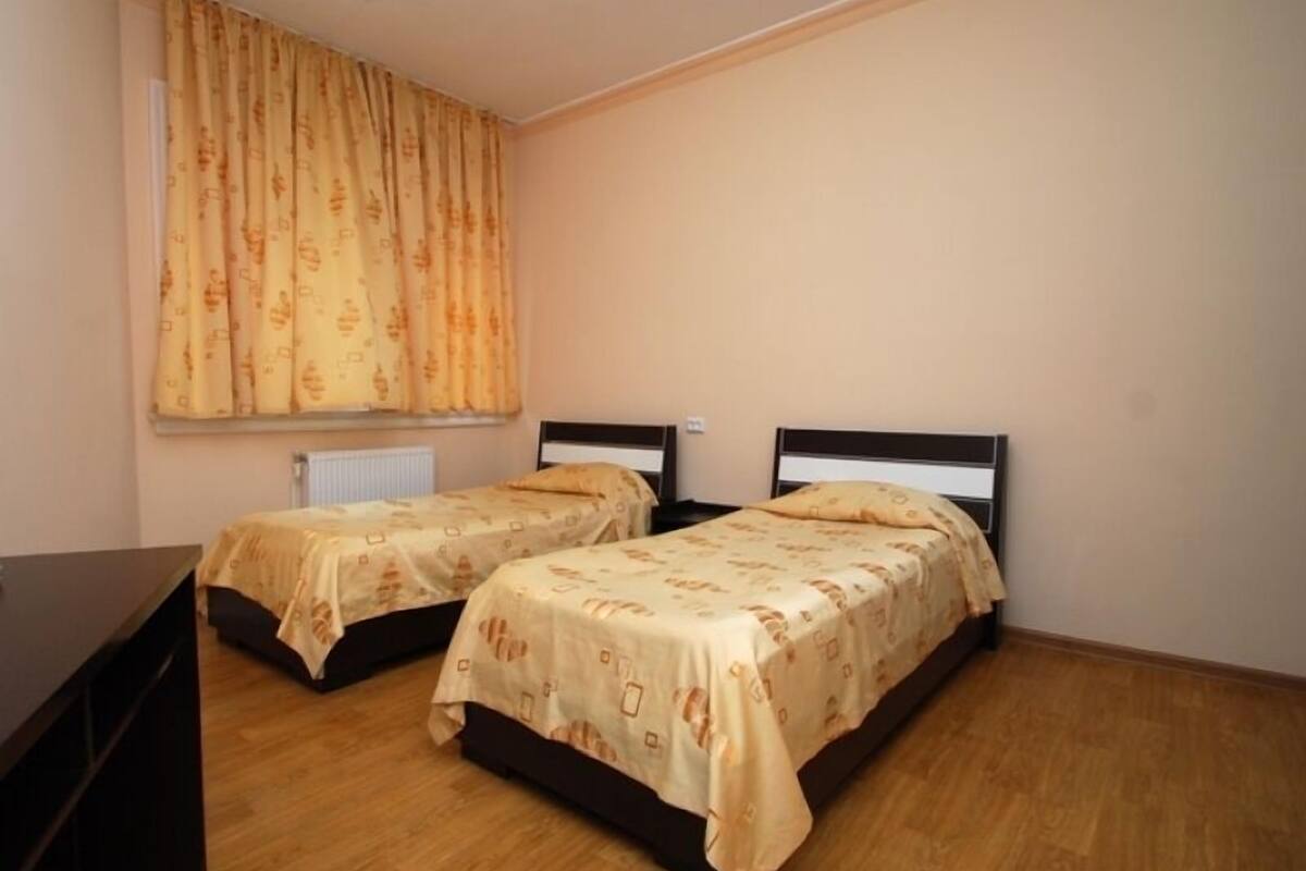 Une chambre avec deux lits, un radiateur et une fenêtre avec des rideaux.