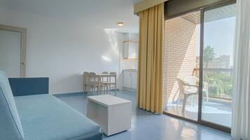 Habitación de hotel moderna con cama, una mesita, una silla y un balcón con vistas.