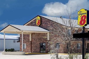 A Super 8 hotel with a brick facade, a covered entrance, and a clear blue sky.
