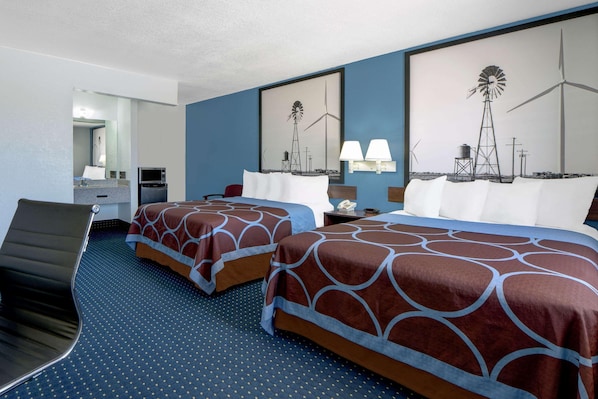 A hotel room with two beds, a desk, a chair, and a large window with a windmill view.