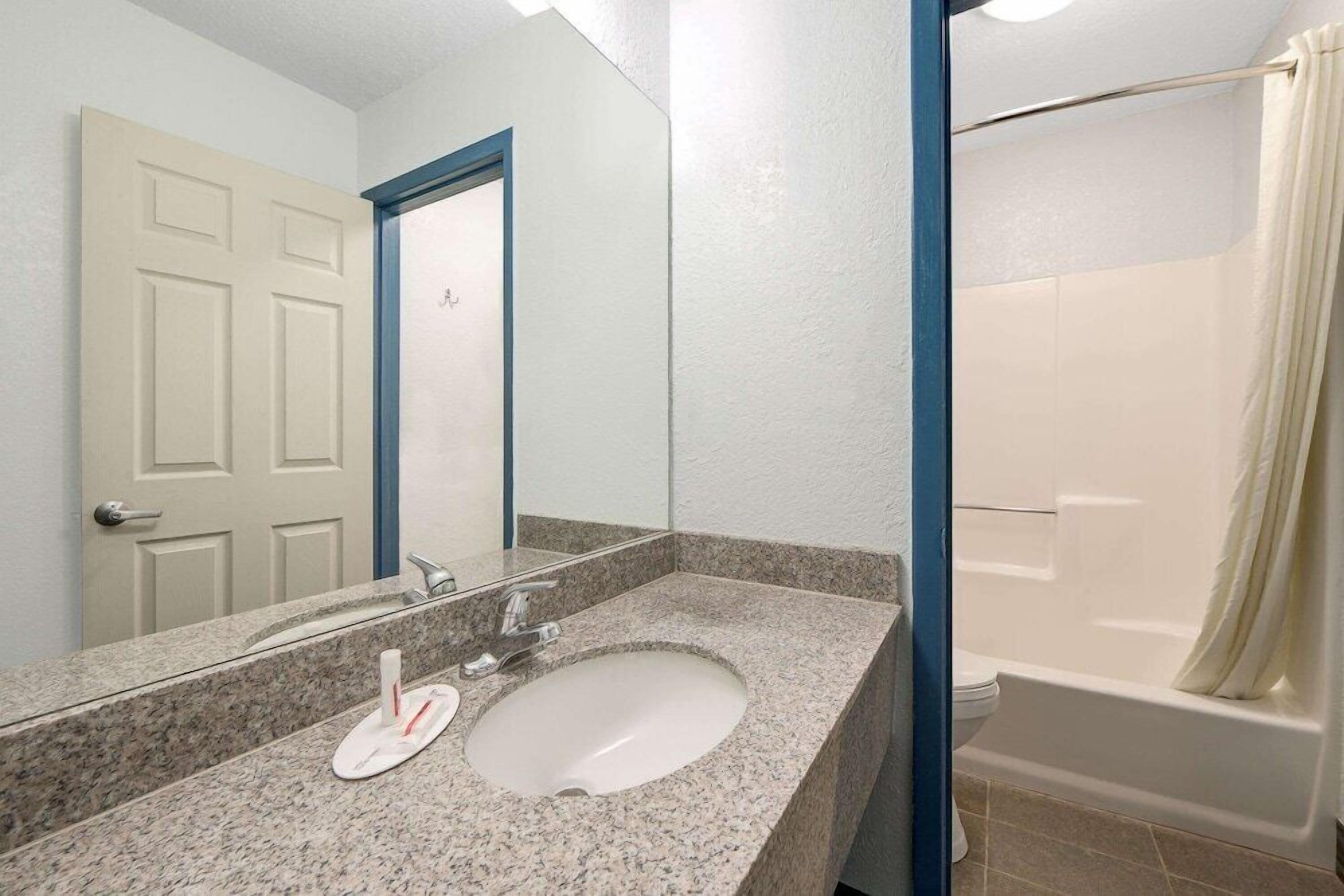 Un baño con lavamanos, espejo y ducha.