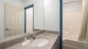 Un baño con lavamanos, espejo y ducha.