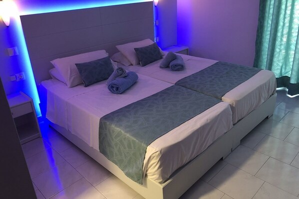 A double bed with a patterned bedspread, two pillows, and rolled towels. - Silver Beach Hotel (Corfu)