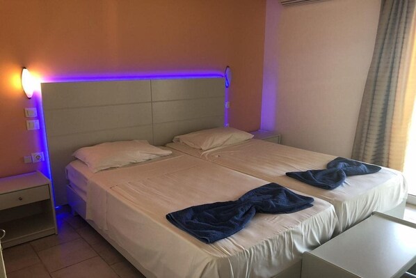 A double bed with a headboard, two pillows, and a bedside table with a lamp. - Silver Beach Hotel (Corfu)