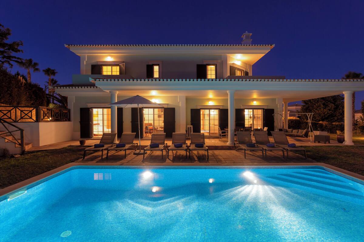 A two-story house with a swimming pool, outdoor seating, and a covered patio.