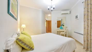 Une chambre à coucher comprenant un lit, un bureau, une chaise, une lampe, un miroir et un radiateur.