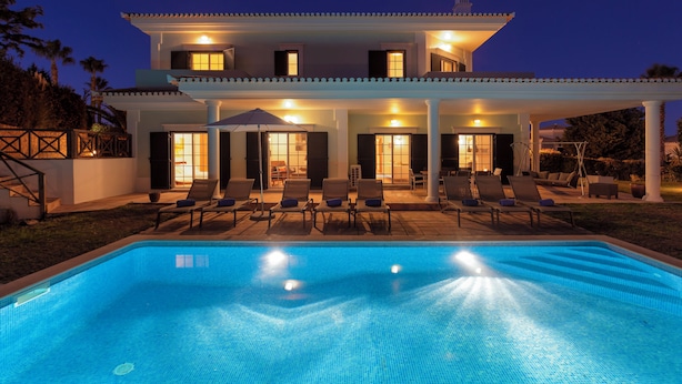 Une maison à deux étages avec une piscine, un espace salon extérieur et une terrasse couverte.