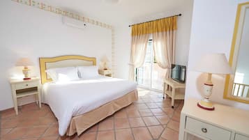 Una habitación de hotel con una cama, mesitas de noche con lámparas, un televisor, un escritorio y una silla.
