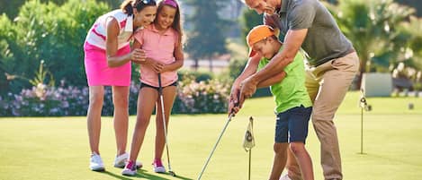 Ein Golfplatz mit Putting Green, Flagge und einer spielenden Familie.
