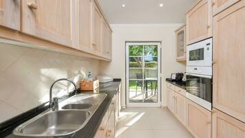 A modern kitchen with wooden cabinets, stainless steel sink, and a microwave.