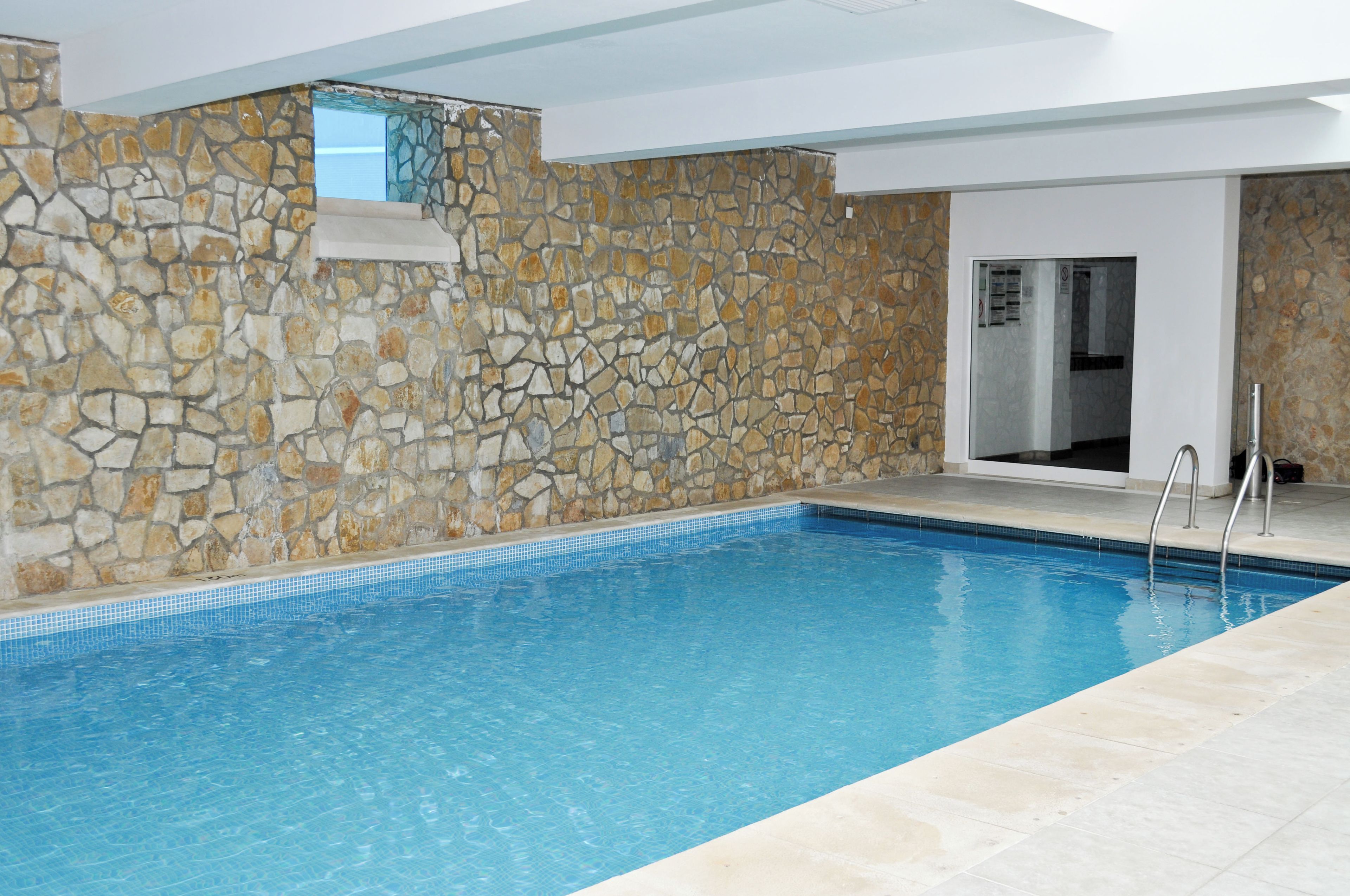 A swimming pool with stone walls and a tiled floor.