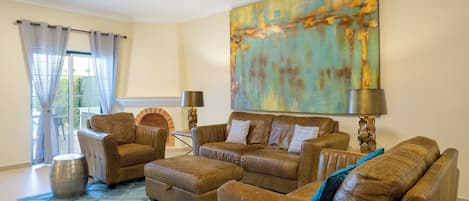 A living room with leather sofas, a patterned rug, and a large abstract painting.