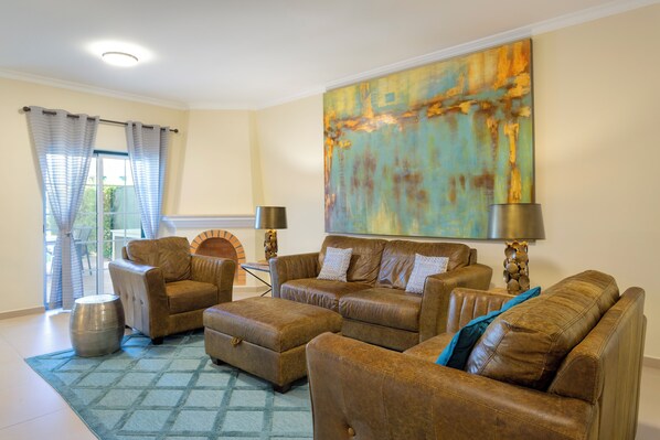 A living room with leather sofas, a patterned rug, and a large abstract painting. - Martinhal Quinta Do Lago Family Resort (Loulé)