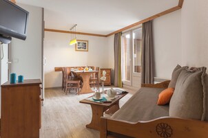 Une pièce confortable avec un canapé, une table en bois, une télévision et un coin repas.
