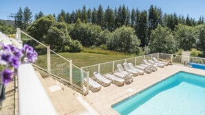 A swimming pool with lounge chairs, a clear view of the surrounding trees, and a cable car in the background. - Residence Les Bergers (Huez)