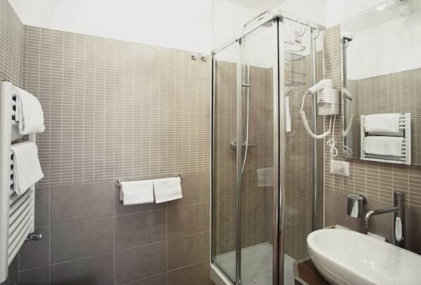 A modern bathroom with a glass-enclosed shower, a sink, and a towel rack. - Relais Bocca di Leone (Rome)