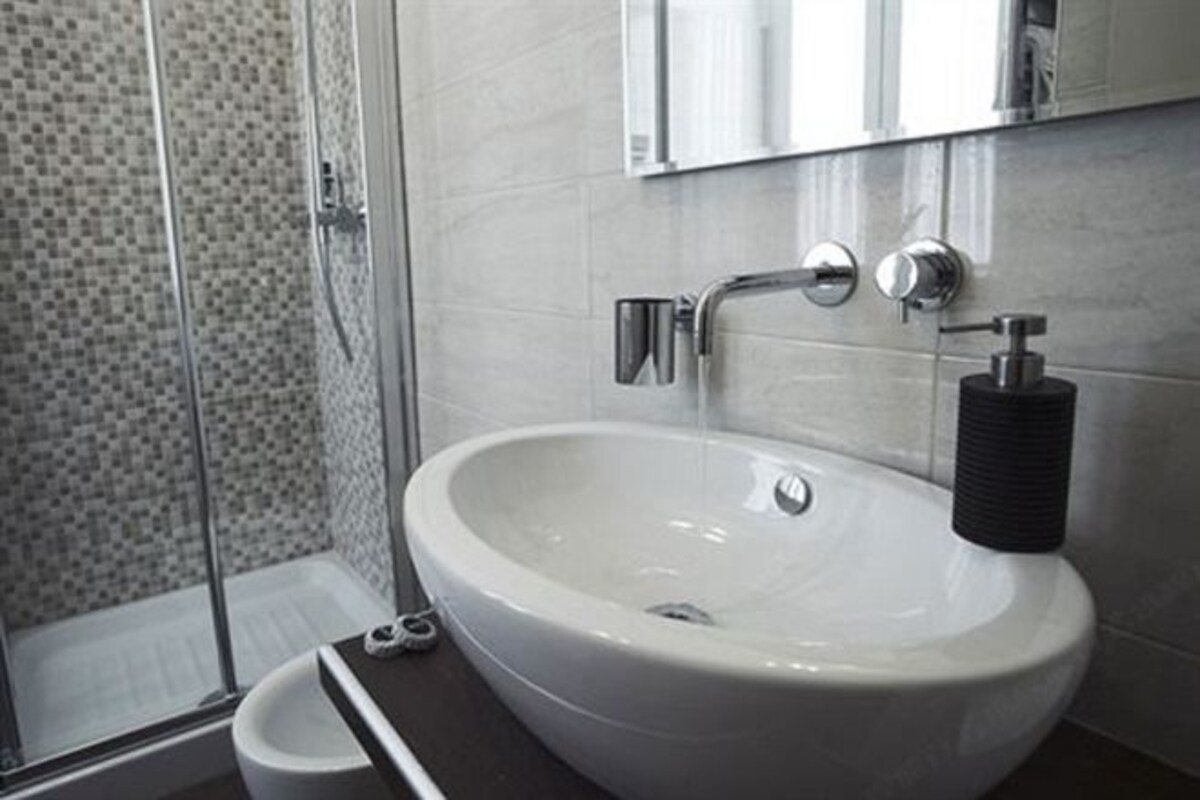 A bathroom with a white sink, a mirror above it, and a shower area with a glass door.