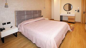 A modern bedroom with a bed, bedside table, and a vanity with a mirror.