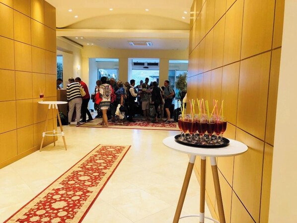 A hotel lobby with a central gathering area, a red patterned carpet, and a table with glasses of red beverage. - Grand White City Hotel (Berat)