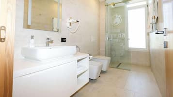 A modern bathroom with a white vanity, a large mirror, a hairdryer, and a glass shower enclosure.