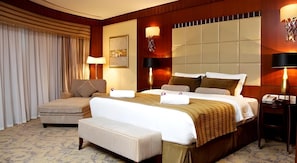 A hotel room with a large bed, two bedside tables, a sofa, and a small table.