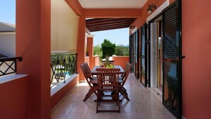 Un balcon avec une table et des chaises, une piscine et une vue sur les environs.