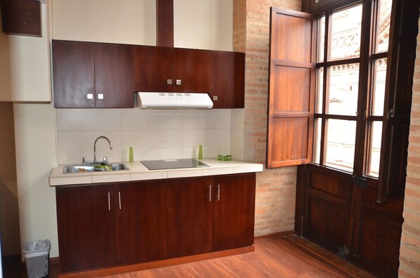 A kitchen with wooden cabinets, a stainless steel sink, and a window with a view of the outside. - Hotel San Ezequiel (Cuenca)