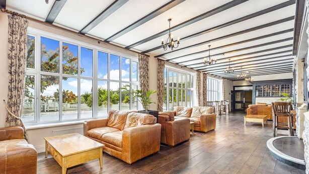 Ein großzügiger Wohnbereich mit Ledersofas, einem Holztisch und einem großen Fenster mit Blick ins Freie.
