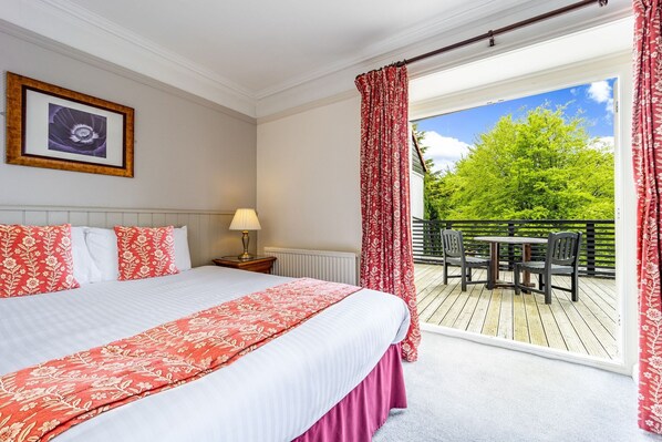 A hotel room with a large bed, a table and chairs outside, and a view of greenery. - Best Western The Webbington Hotel and Spa (Axbridge)