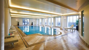 Ein großes Hallenbad mit Fliesenboden, Bänken und Topfpflanzen.