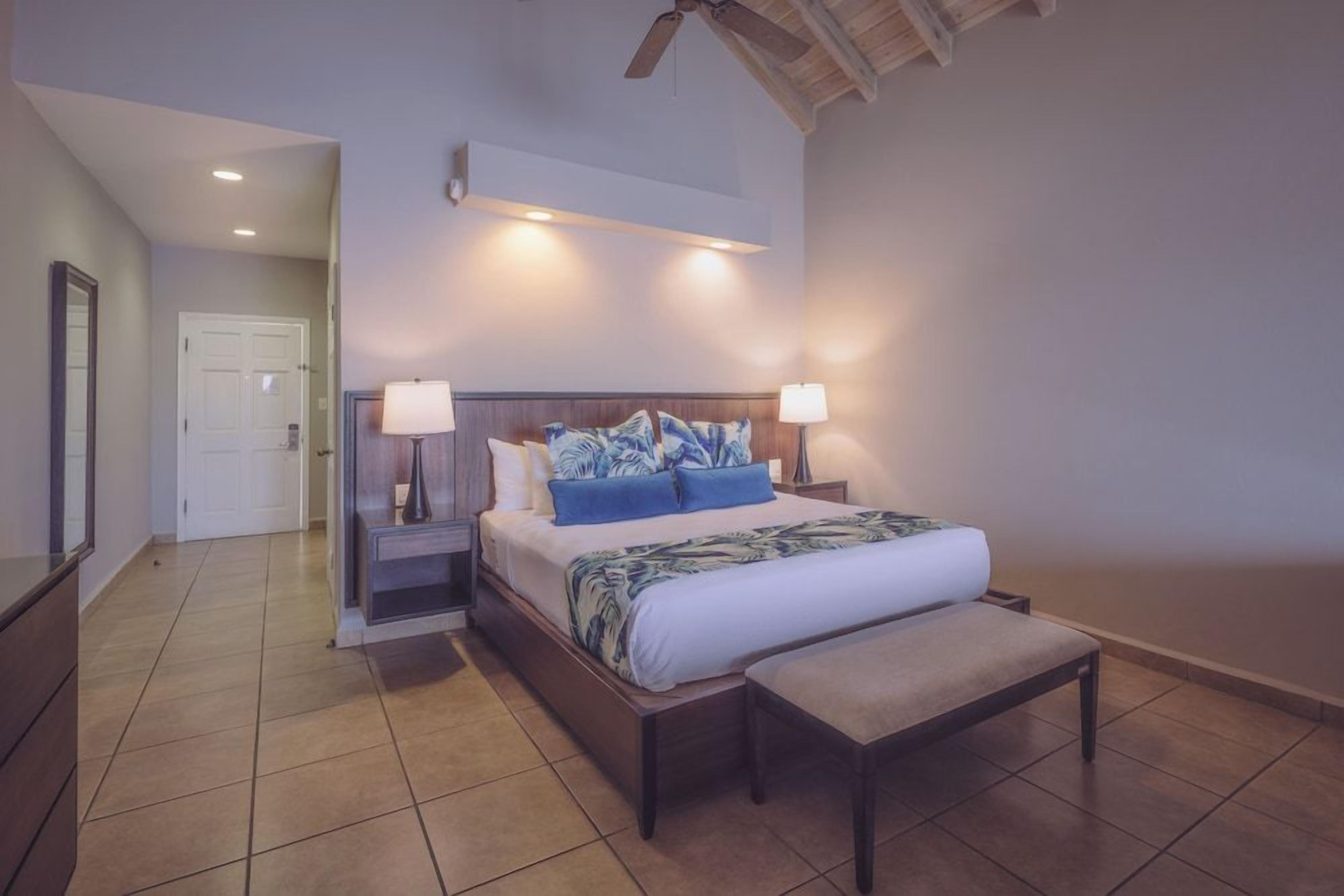A bedroom with a bed, bedside tables, a bench, and a ceiling fan.