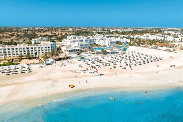 A coastal resort with a large beach, multiple hotel buildings, and a clear blue sky. - Club Calimera Yati Beach (Djerba Midun)