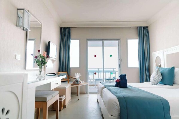Une chambre d’hôtel avec un lit, un bureau, une chaise, une télévision et un balcon avec vue.
