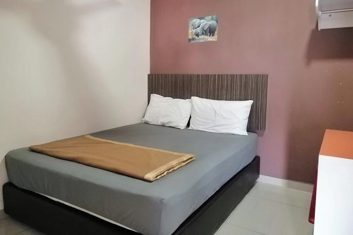 A neatly made bed with a grey mattress and white pillows, a brown blanket, and a headboard with vertical lines.