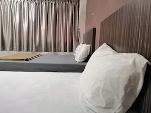Habitació d'hotel amb un llit, un coixí, una taula de nit i cortines.