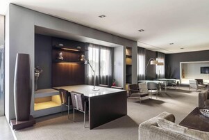 Una habitación de hotel moderna con comedor, sofá y televisor de pantalla plana.