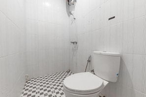 A bathroom with a white toilet, a shower, and a checkered floor.