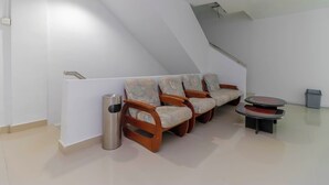 Una habitación con techo inclinado, un conjunto de sofás, un bote de basura y una mesita.