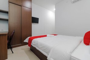 A bedroom with a bed, a wardrobe, a television, and a chair. - Reddoorz Plus Near Kepri Mall (Batam)