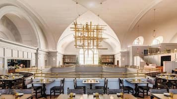 A spacious interior with high ceilings, a central open area, and seating arranged around it.