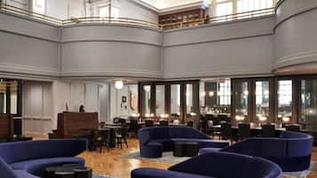 A spacious lobby with high ceilings, a central seating area with sofas, and a bar with multiple seating options.