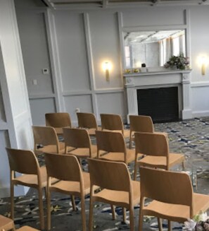 A room with rows of wooden chairs arranged for seating, a fireplace, and wall sconces. - The Line DC (Washington)