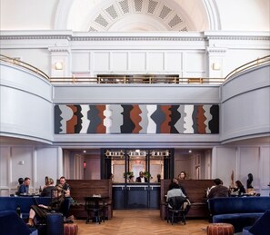 A lobby with a reception desk, seating area, and a high ceiling with decorative moldings. - The Line DC (Washington)