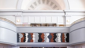A lobby with a reception desk, seating area, and a high ceiling with decorative moldings.