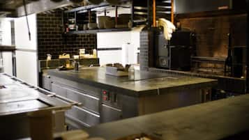 A commercial kitchen with stainless steel appliances, a brick wall, and hanging pots.