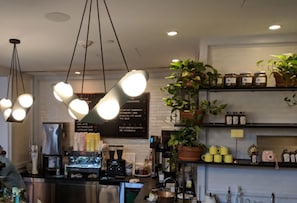 A coffee shop interior with hanging lights, a coffee machine, shelves with jars, and a menu board. - The Line DC (Washington)